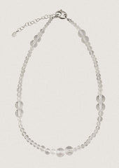 A beaded necklace made of round clear quartz beads in varying sizes.