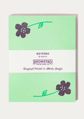 A green notepad with purple flower print at corners.