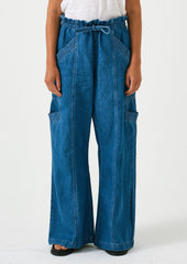 A woman wearing a pair of relaxed leg pants with cargo style details, in bright blue denim.