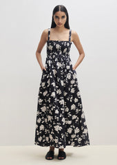 A woman wearing a black and white floral print maxi dress with smocked bodice.