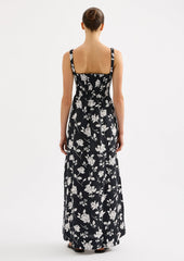 A woman wearing a black and white floral print maxi dress with smocked bodice.