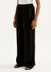 A person wearing a pair of black sateen pants with split leg hem.