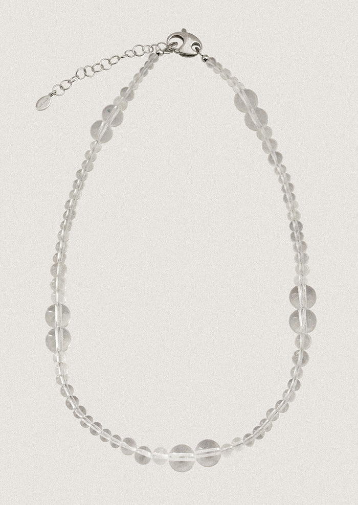A beaded necklace made of round clear quartz beads in varying sizes.