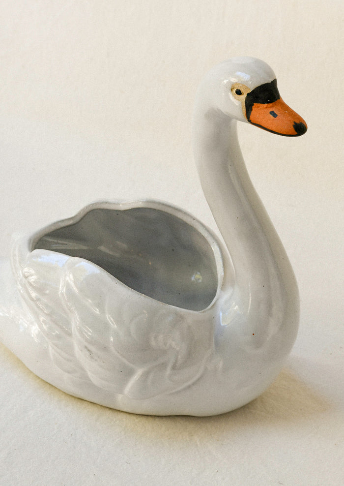 Top view of a ceramic planter in the shape of a cygnet sitting atop a table.