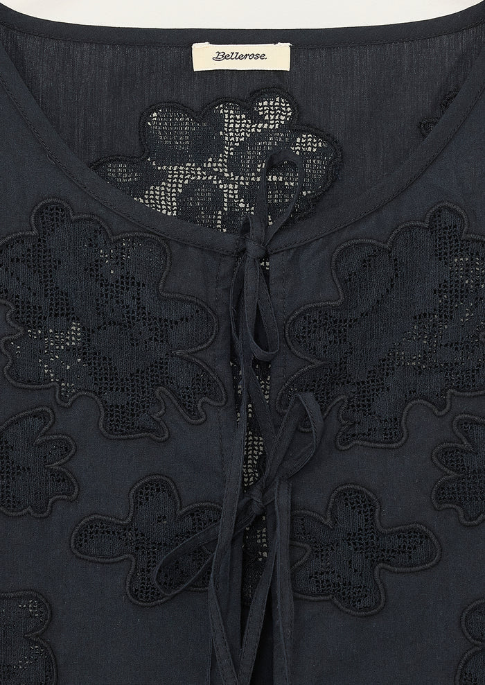 A sleeveless tie front top in black with tonal lacework detailing and peplum hem.