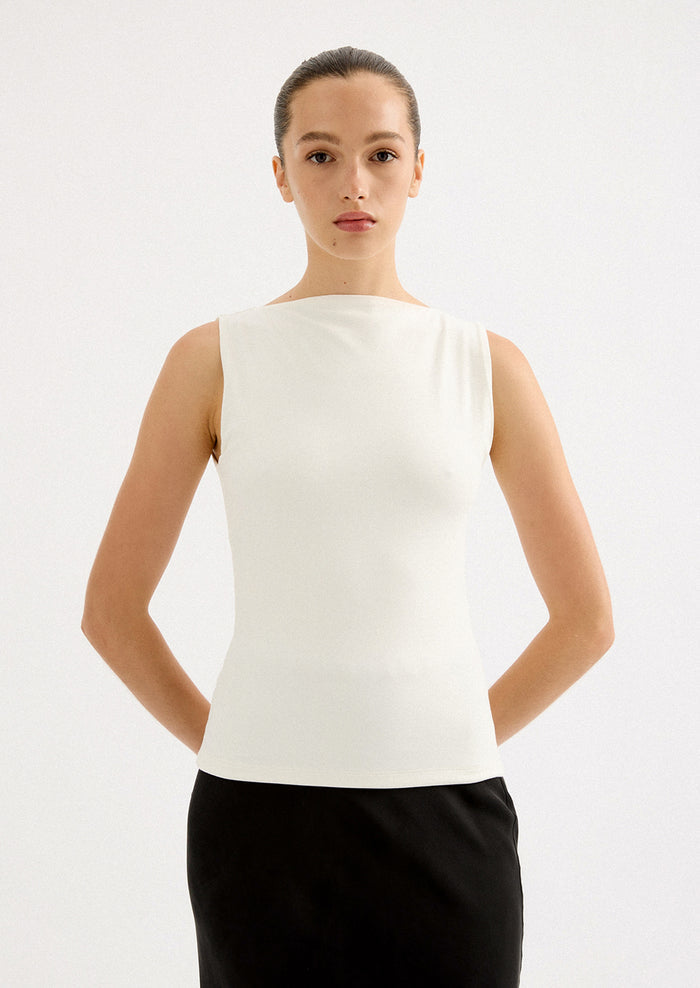 A woman wearing a solid white sleeveless tank top with high round neckline.