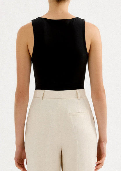 A woman wearing a solid black sleeveless tank top with high round neckline.