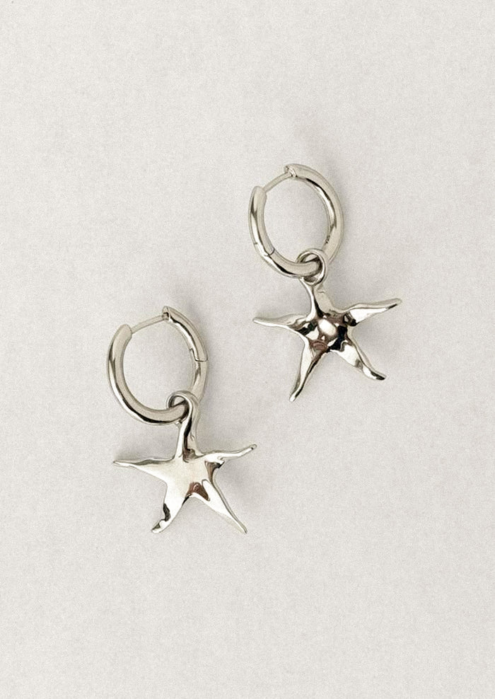 A pair of silver star earrings on hoop.
