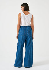 A woman wearing a pair of relaxed leg pants with cargo style details, in bright blue denim.
