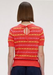 A woman wearing a red short sleeve knit top with yellow and pink wavy stripes.