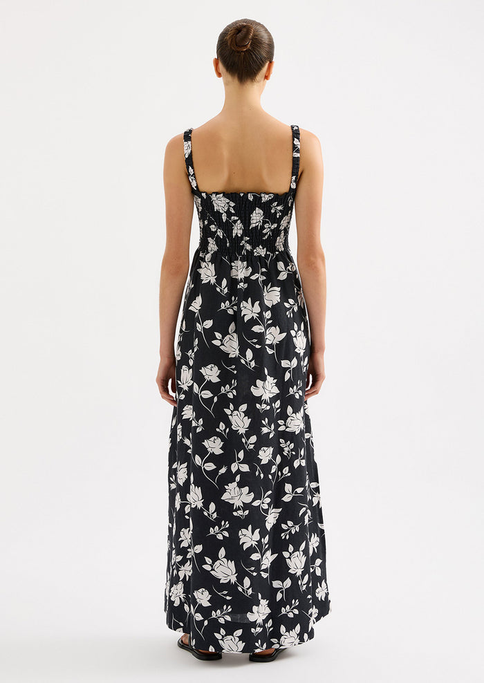 A woman wearing a black and white floral print maxi dress with smocked bodice.