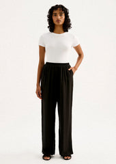 A person wearing a pair of black sateen pants with split leg hem.