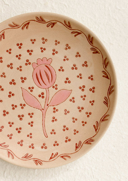 A round plate in sand color with pink floral print.
