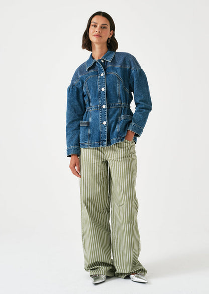 A woman wearing a denim jacket with decorative stitching and ruched shoulder detail.